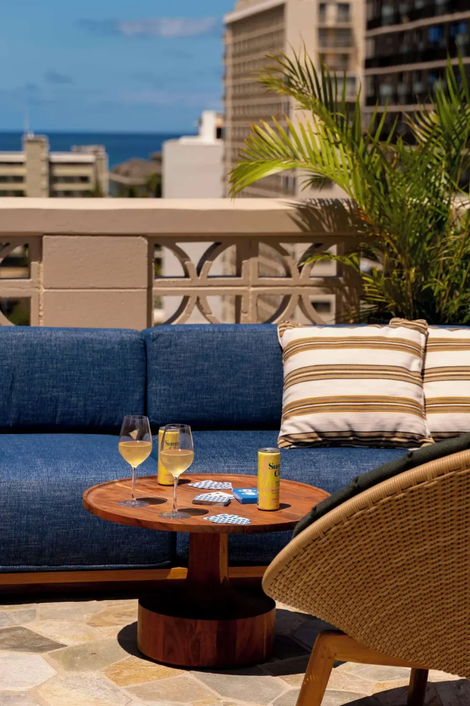 Outdoor terrace seating with drinks and ocean in the distance at Wayfinder Waikiki.