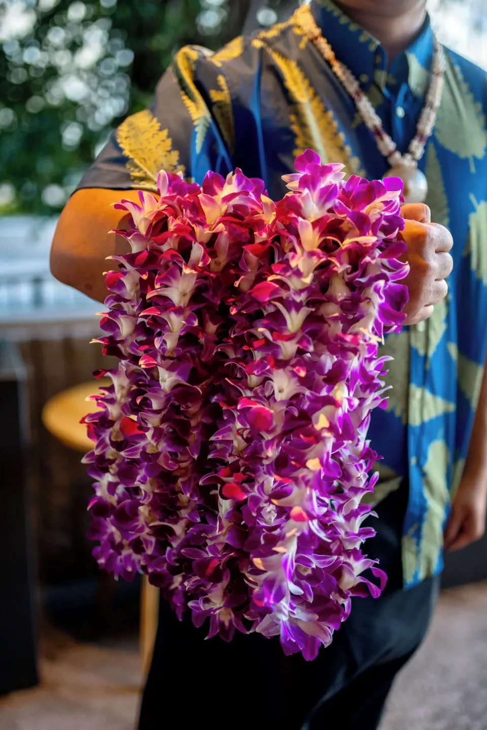 A staff member holds purple orchid leis at Wayfinder Waikiki.