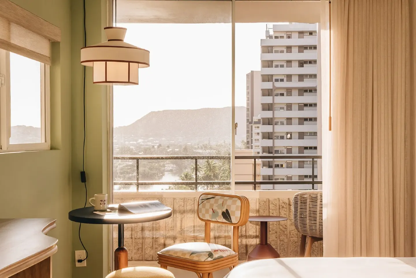Sunlit guest room corner and balcony view at Wayfinder Waikiki.