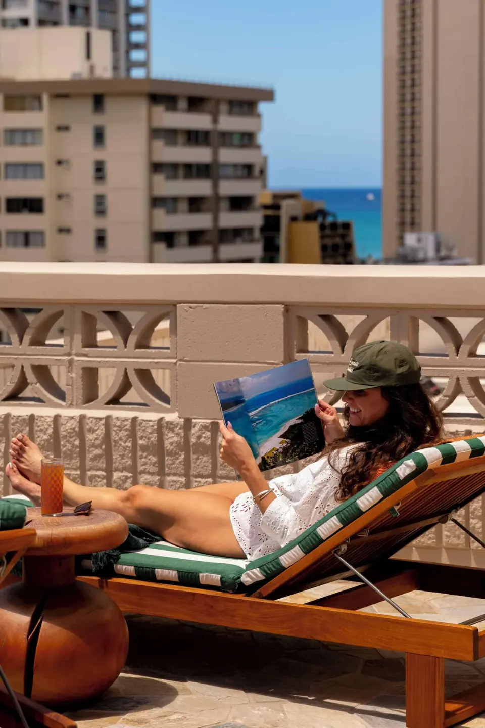 Guest relaxing on a terrace lounger with ocean glimpses at Wayfinder Waikiki.