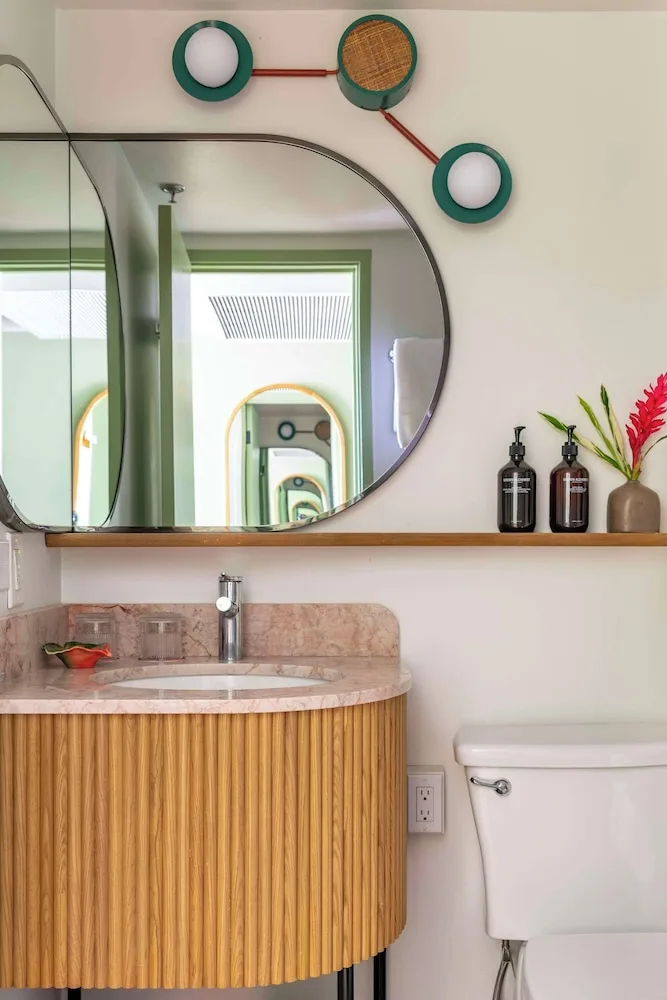 Lanai Corner bathroom vanity with round mirror and shelf at Wayfinder Waikiki.