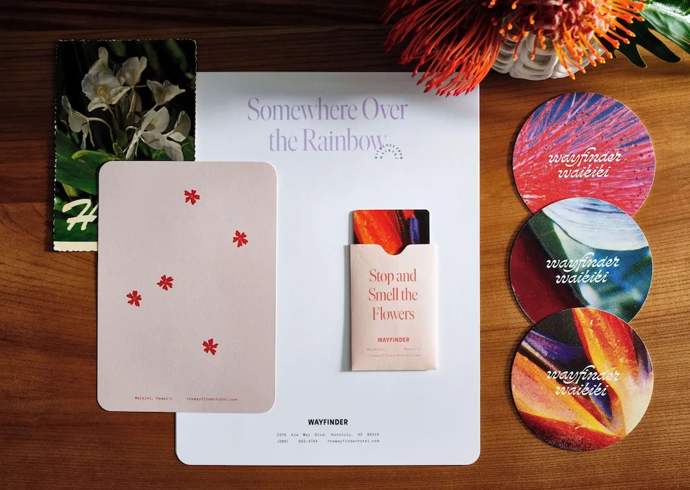 Wayfinder Waikiki stationery, coasters and room cards arranged on a wooden surface.