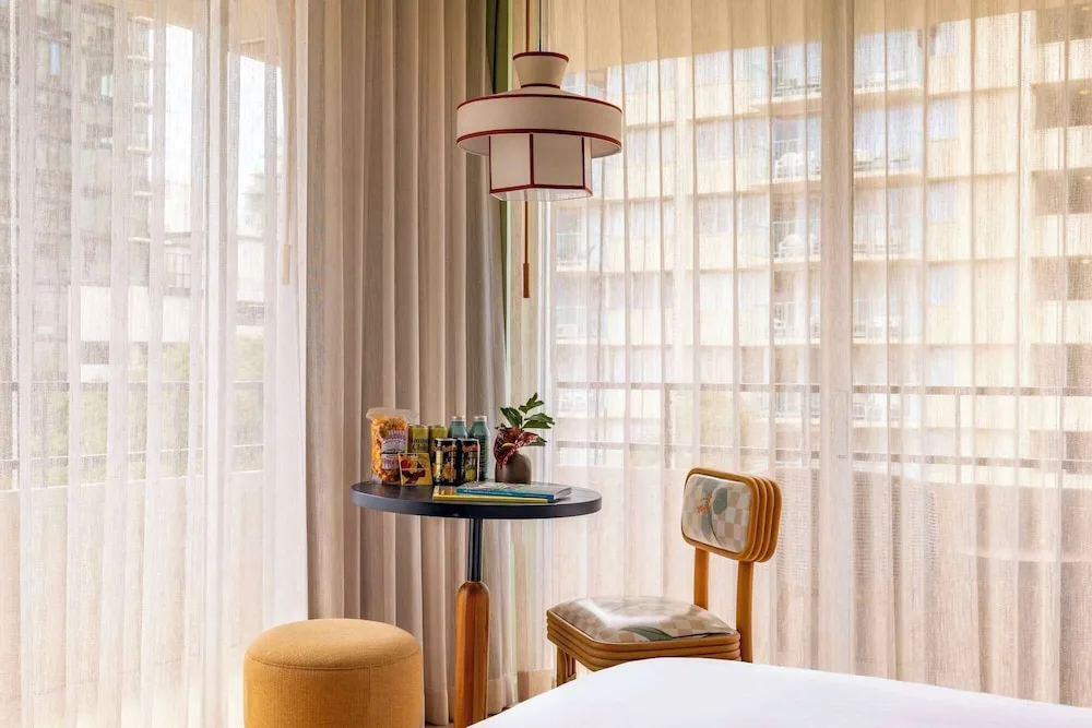 Lanai Corner room seating beside sheer-curtained windows at Wayfinder Waikiki.