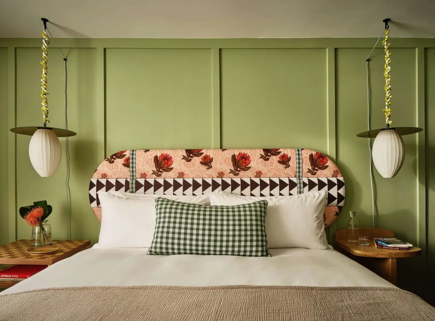 Premium Room king bed with green wall and twin pendant lights at Wayfinder Waikiki.
