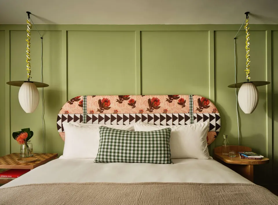 Premium Room king bed with green wall and twin pendant lights at Wayfinder Waikiki.