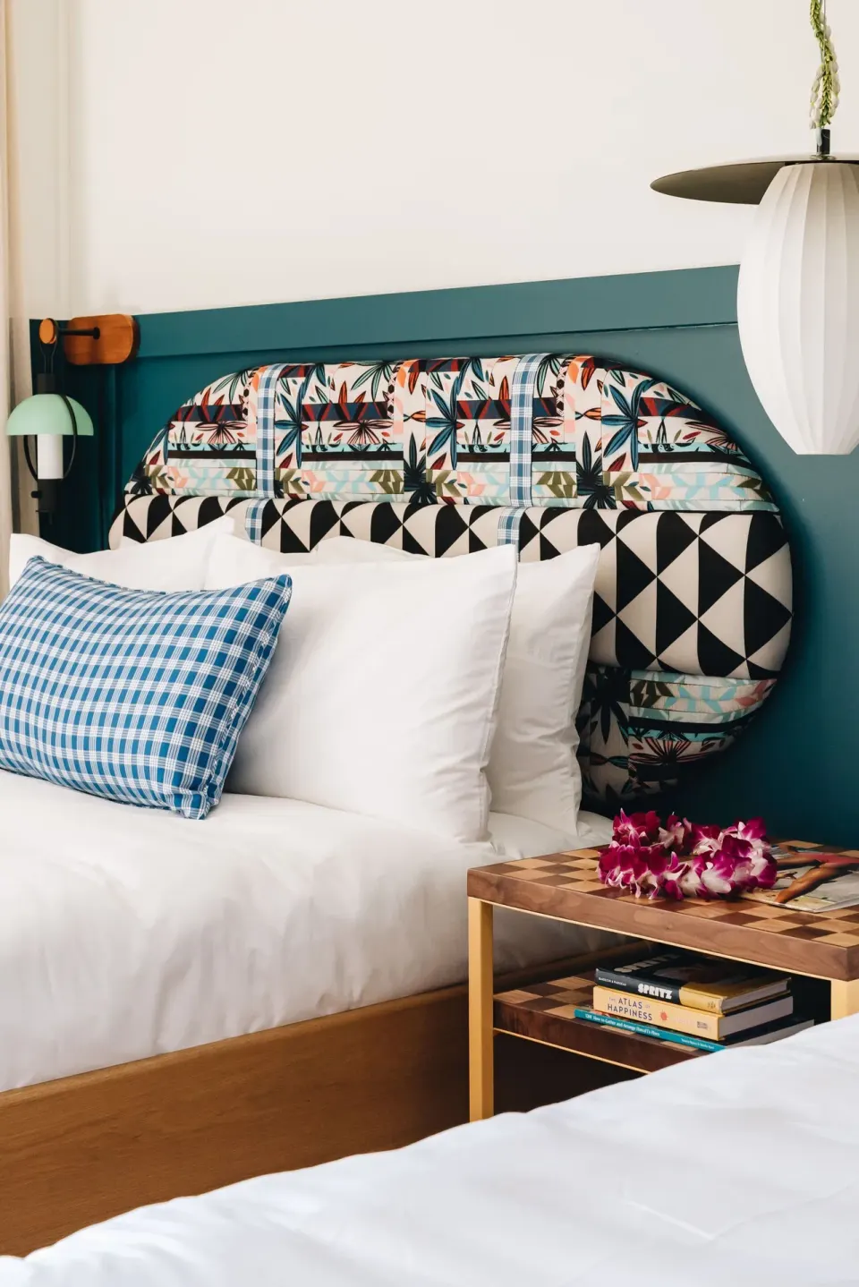 Premium Room bed with patterned headboard and bedside table at Wayfinder Waikiki.
