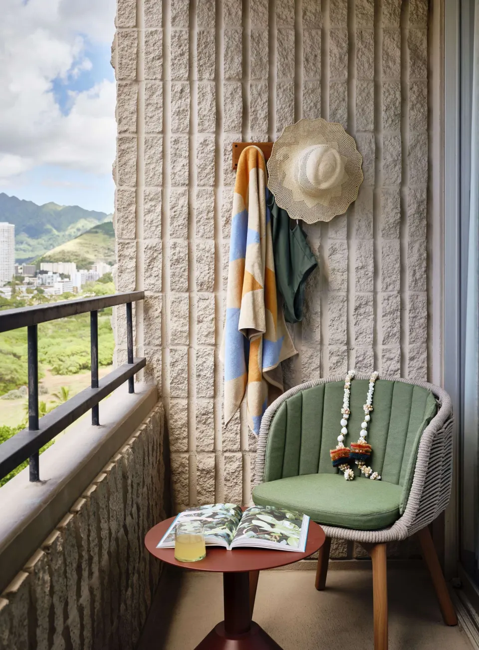 Guest room lanai with chair, table, and mountain view at Wayfinder Waikiki.