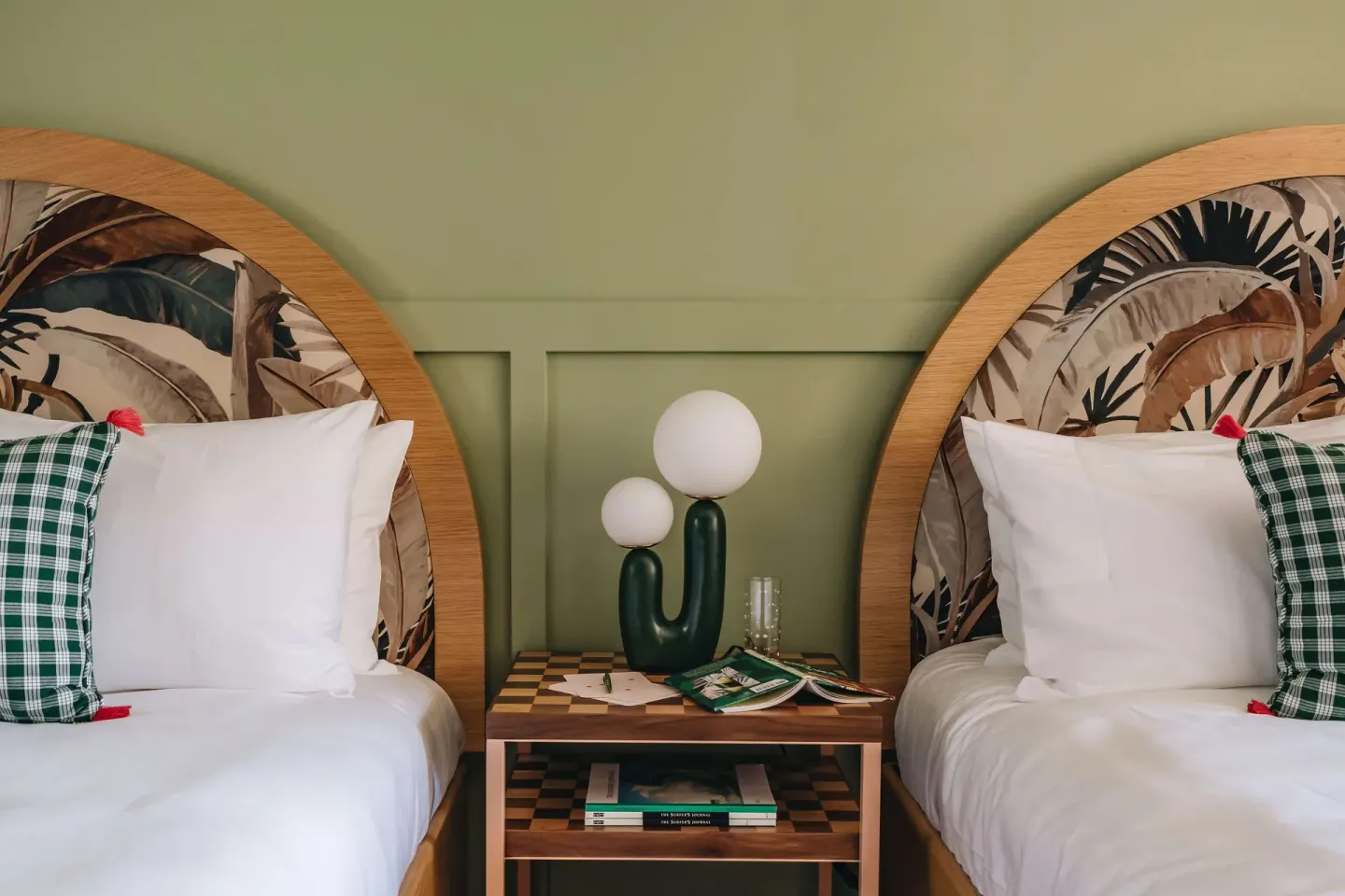 Two beds with arched tropical headboards in a Studio room at Wayfinder Waikiki.