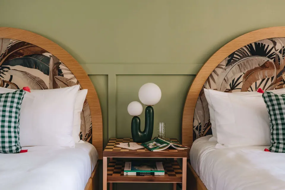 Two beds with arched tropical headboards in a Studio room at Wayfinder Waikiki.