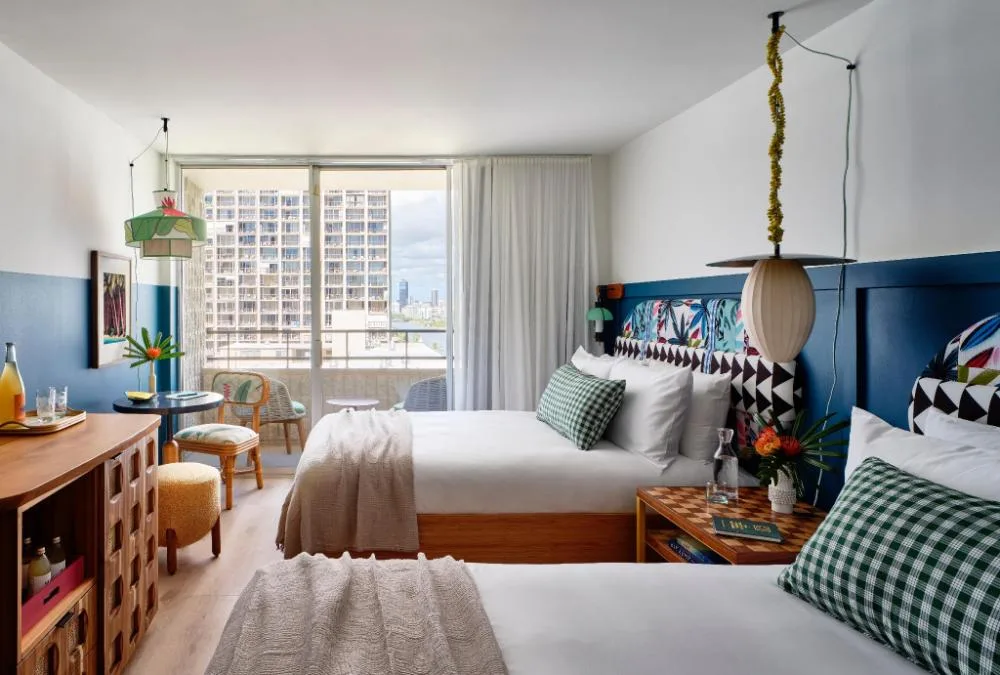 Two Beds with Lanai guest room at Wayfinder Waikiki with patterned headboards and balcony doors.