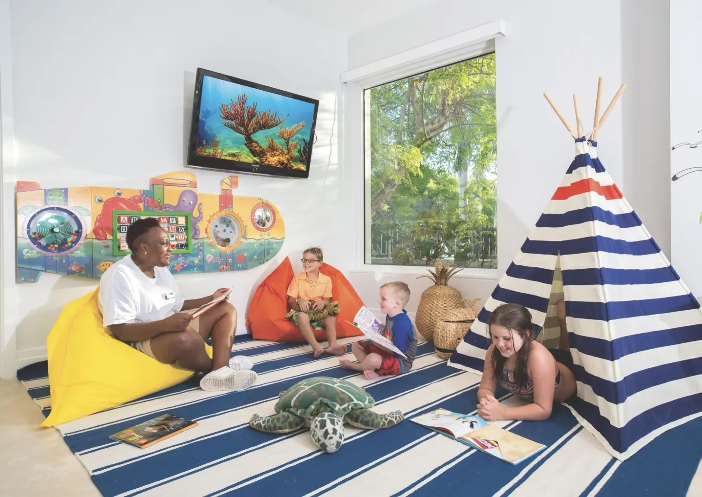 Children read and play in a striped teepee activity room at West Bay Club.