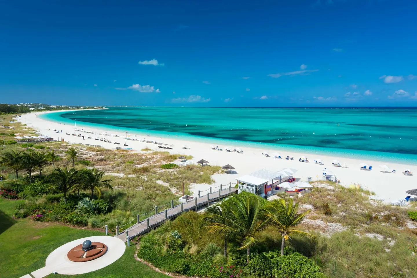 Elevated view of white sand, beach loungers, and turquoise sea at West Bay Club.