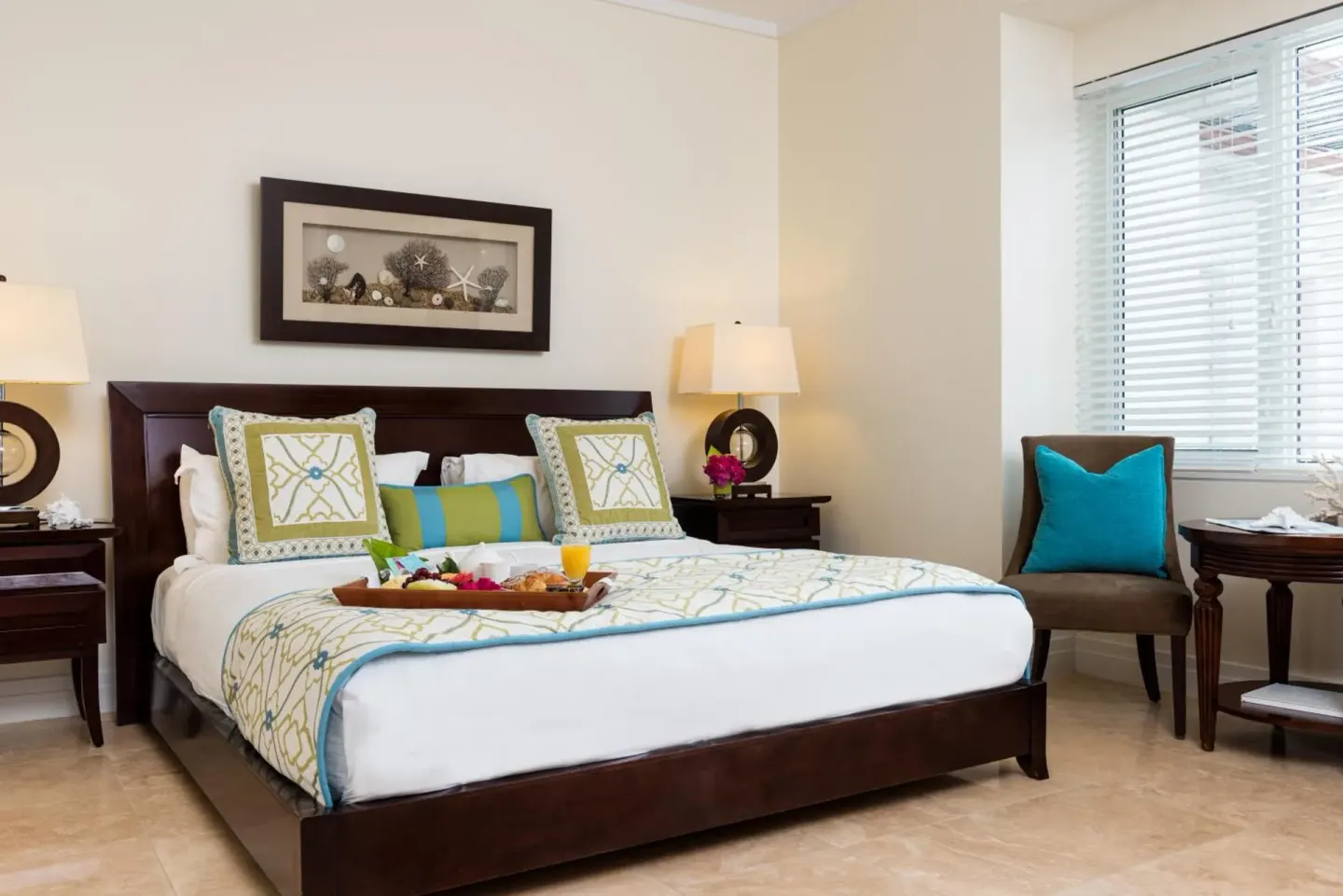 Guest bedroom with a king bed, nightstands, and a chair by the window at West Bay Club.