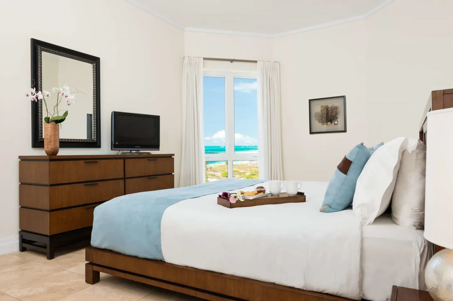King bedroom with breakfast tray and ocean-view window at West Bay Club.