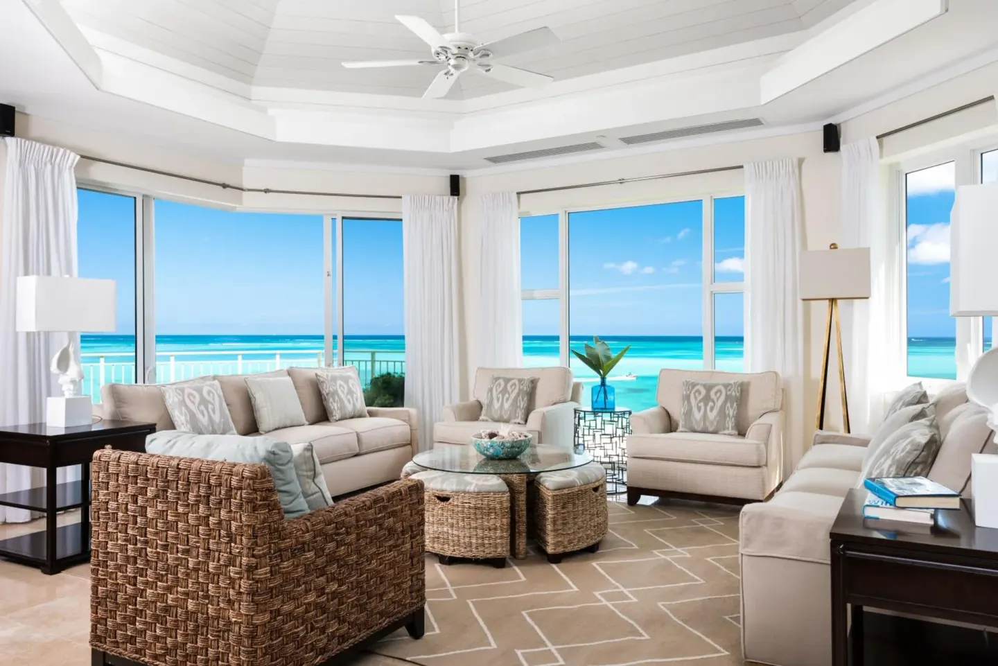 Oceanfront living room at West Bay Club with sofas, armchairs, and large windows.