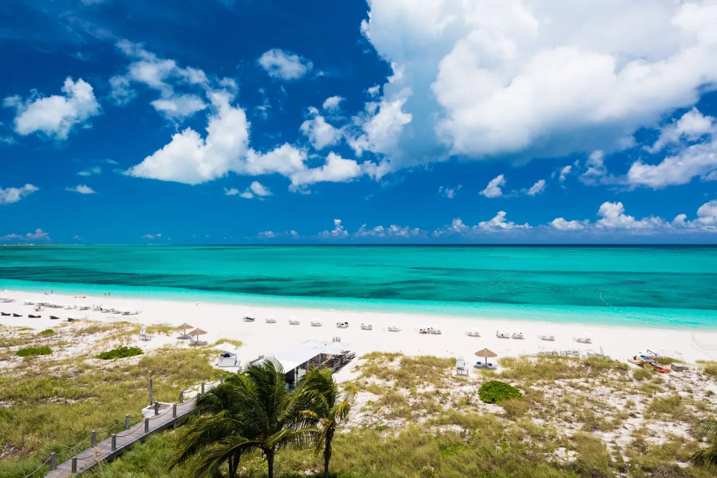 Wide white-sand beach and turquoise ocean under a cloud-filled sky at West Bay Club.