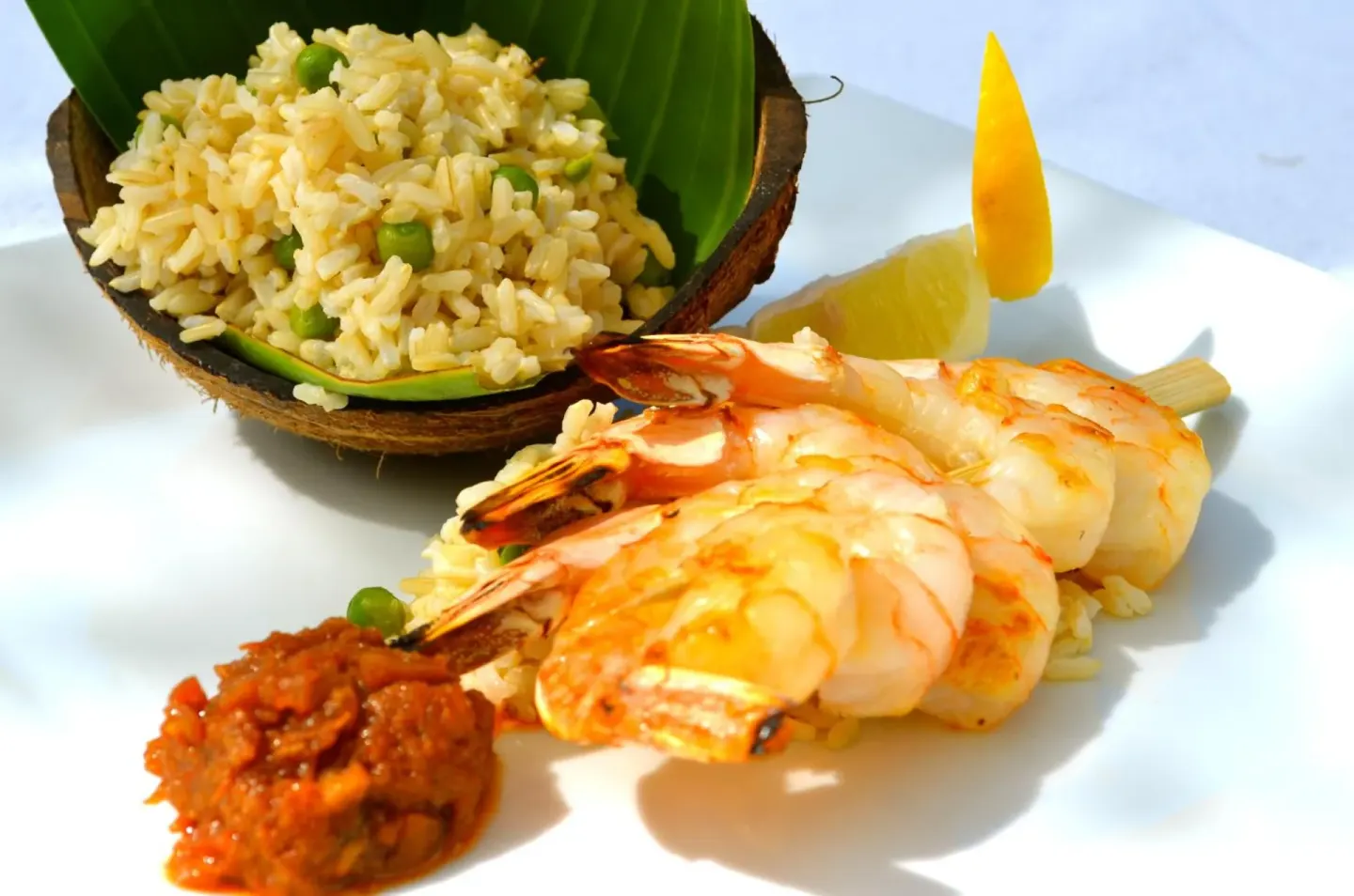 Grilled shrimp, rice, sauce, and citrus are plated for dining at West Bay Club.