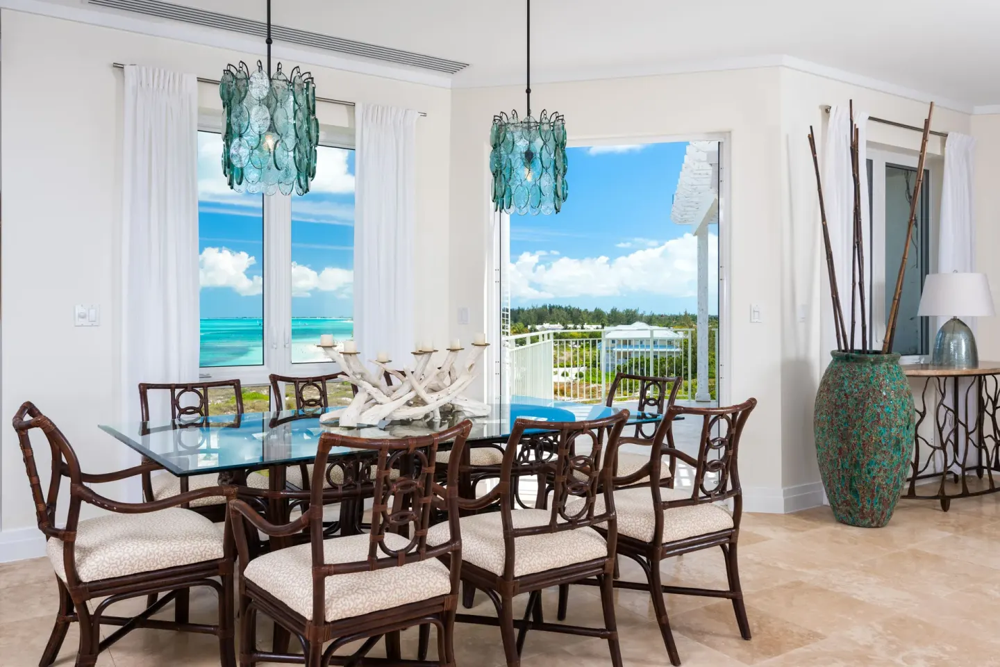Dining area in a Luxury Suite at West Bay Club with glass table and ocean-facing windows.