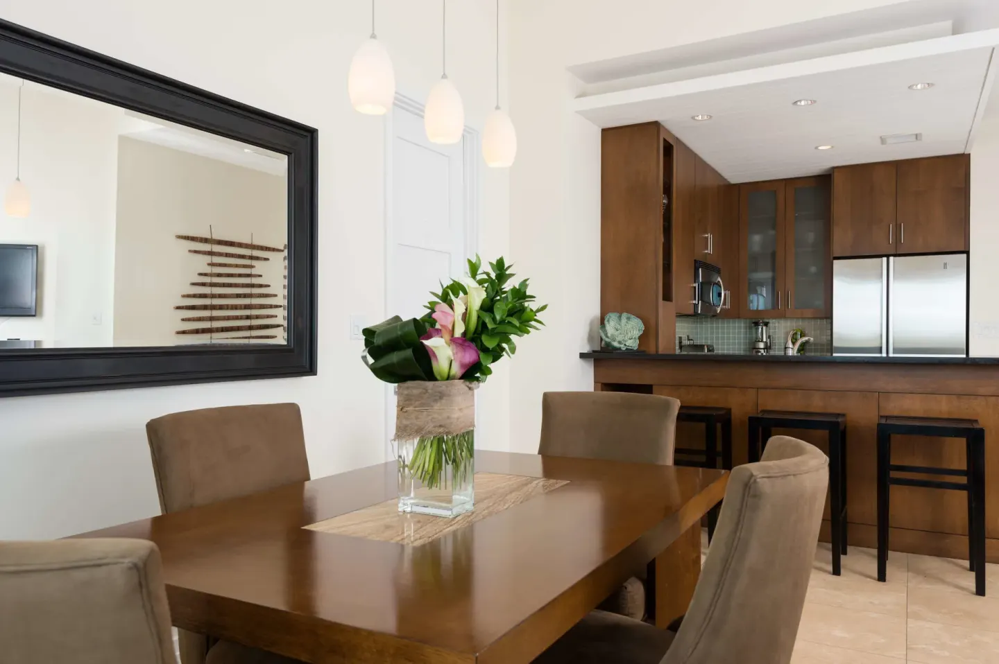 Luxury Suite dining table and kitchen at West Bay Club with pendant lights and bar seating.