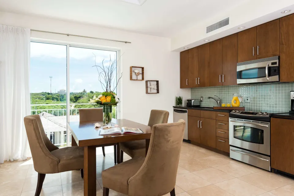 Kitchen and dining space in a Luxury Suite at West Bay Club with balcony doors and green views.
