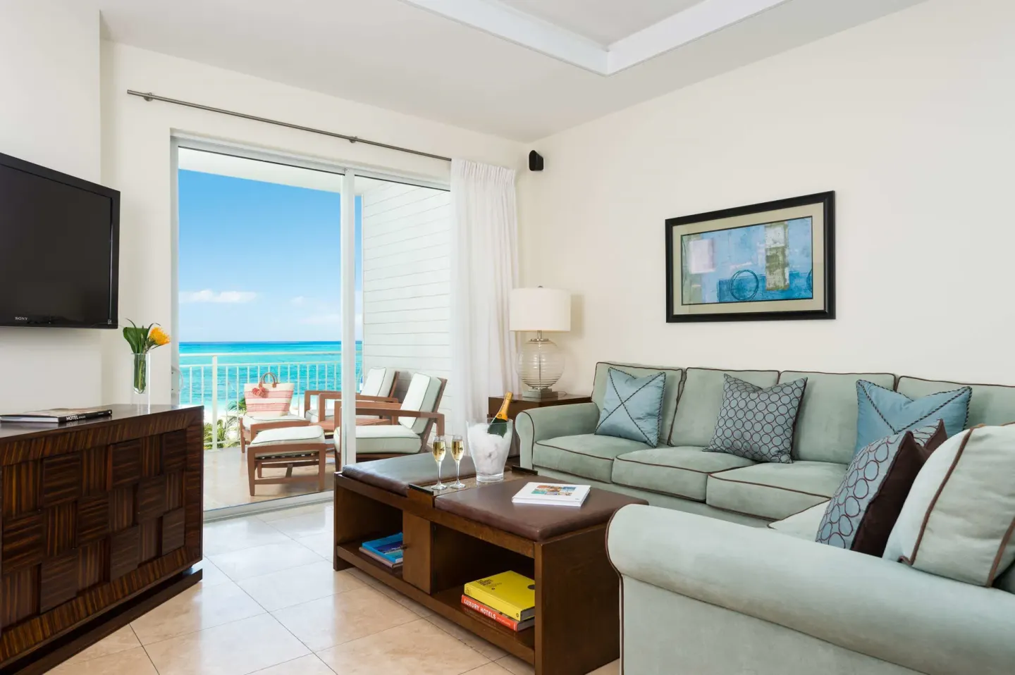 Living room in a Luxury Suite at West Bay Club with sofa, TV, and oceanfront balcony.