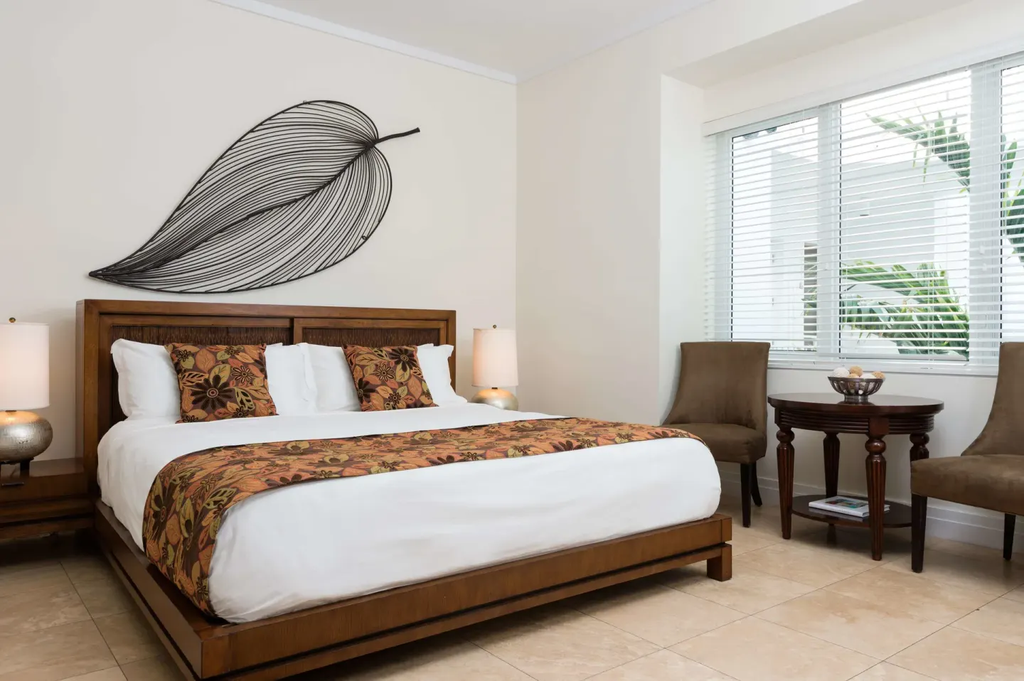 Studio Garden View room with king bed, leaf wall art, chairs, and window blinds at West Bay Club.