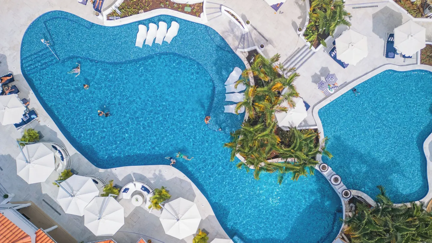 Aerial view of connected resort pools with loungers at Windjammer Landing Resort and Residences.