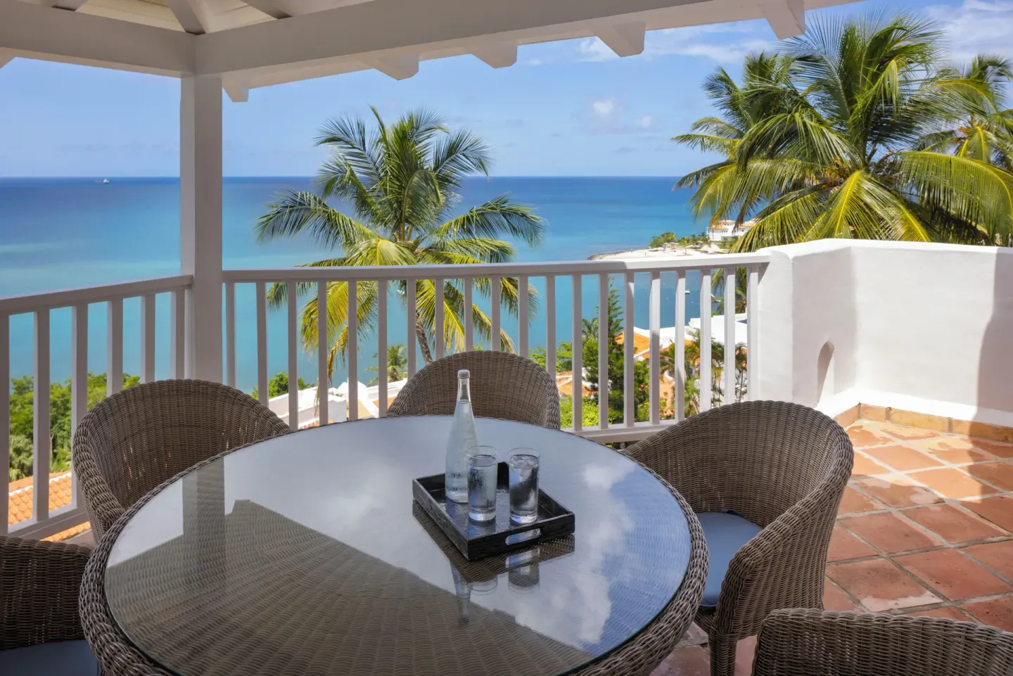 Balcony dining table with wicker chairs and Caribbean Sea view at Windjammer Landing Resort and Residences.