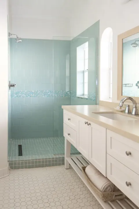 Bathroom with aqua tiled walk-in shower and white vanity at Windjammer Landing Resort and Residences.