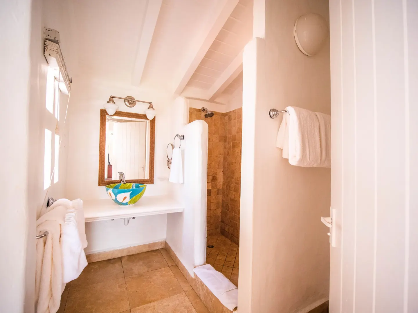 Warm bathroom with colorful vessel sink and walk-in shower at Windjammer Landing Resort and Residences.