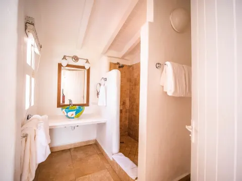 Warm bathroom with colorful vessel sink and walk-in shower at Windjammer Landing Resort and Residences.