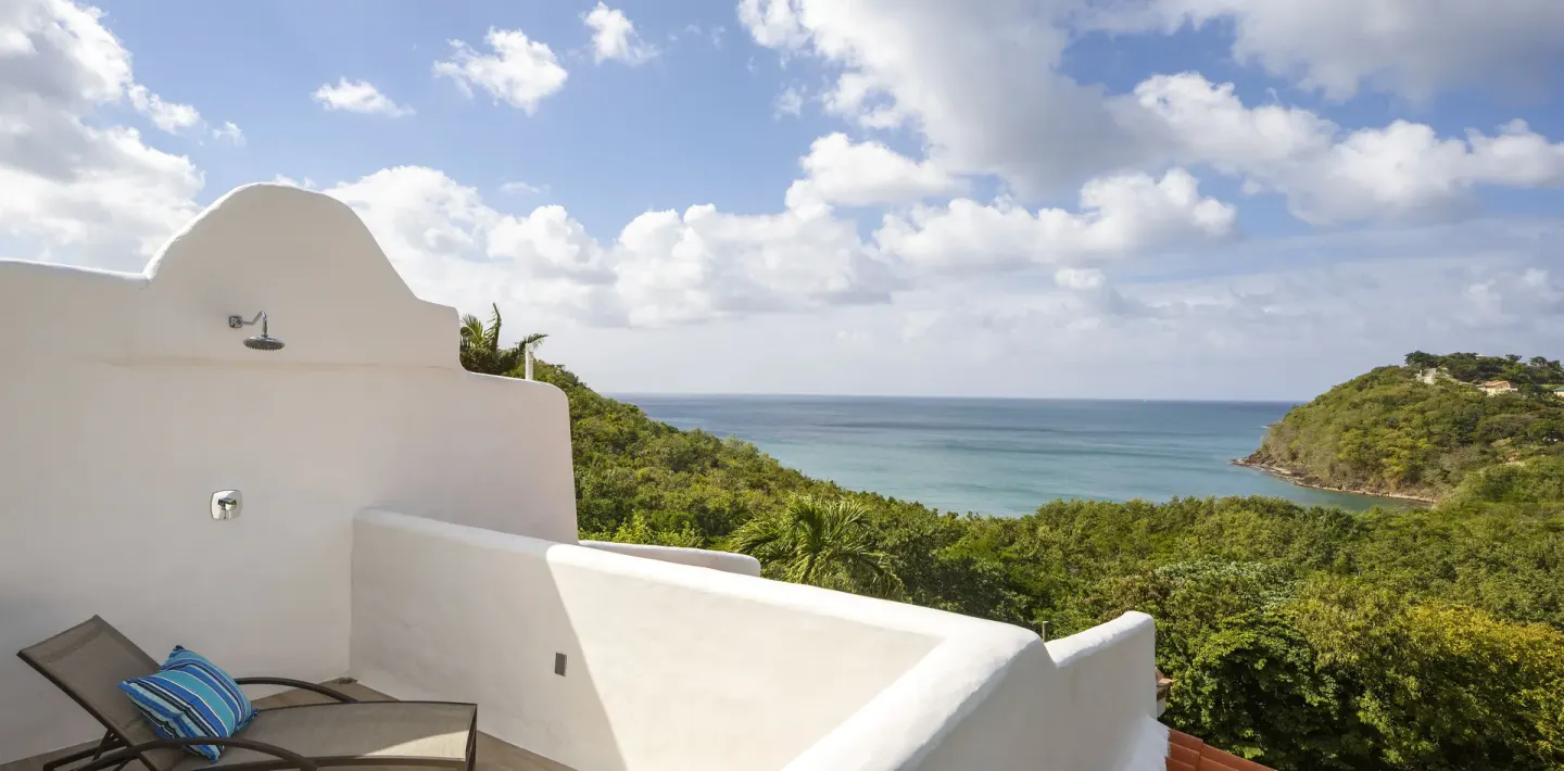 Private terrace with lounge chair, outdoor shower and bay view at Windjammer Landing Resort and Residences.