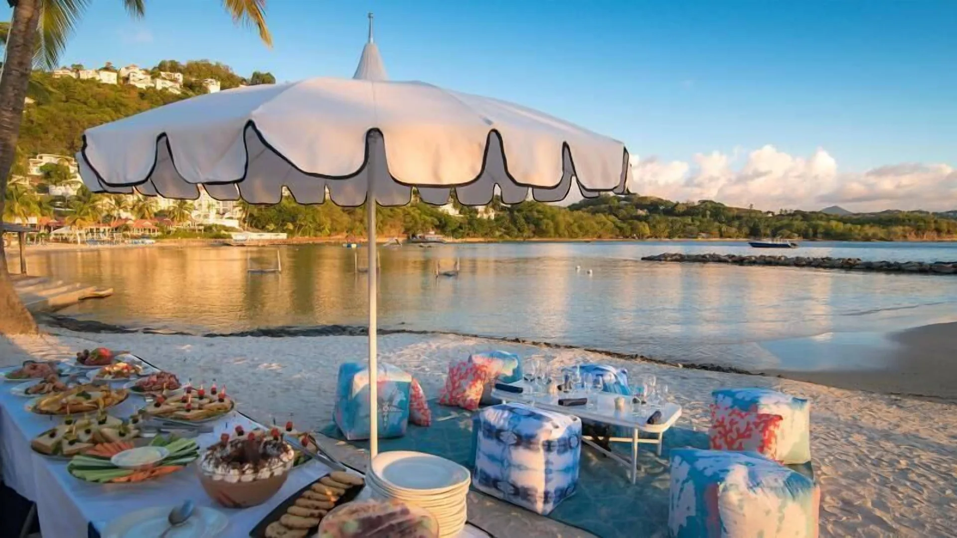 Beach picnic setup under a white umbrella at Windjammer Landing Resort and Residences.