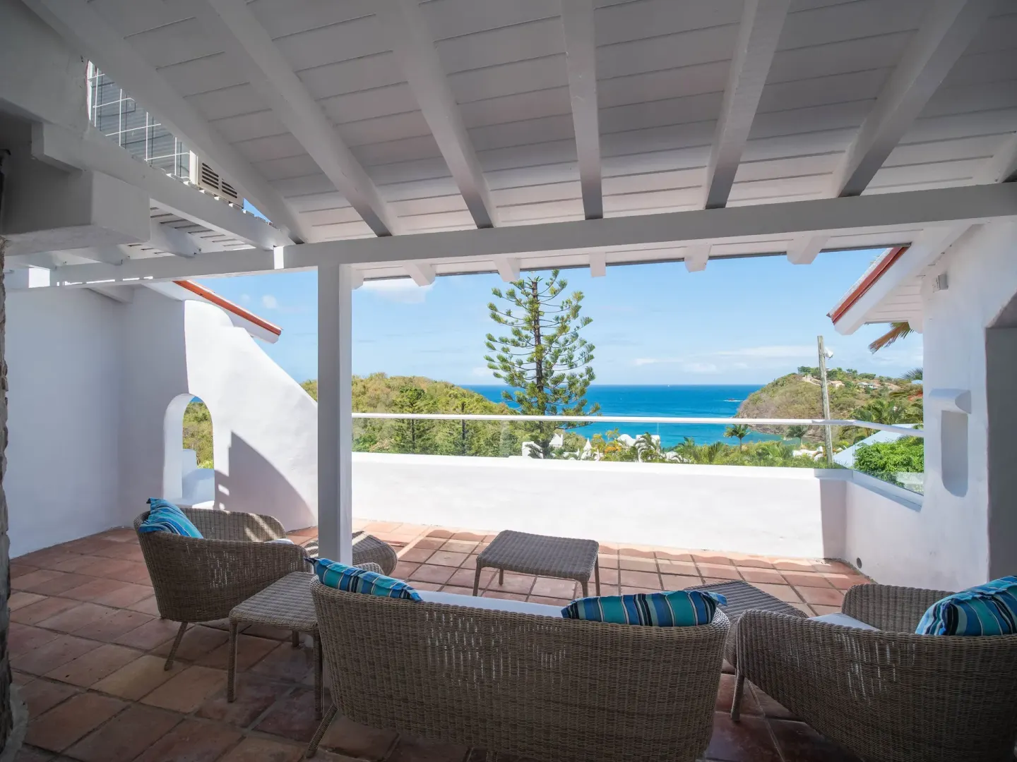 Covered terrace with wicker seating and ocean view at Windjammer Landing Resort and Residences.