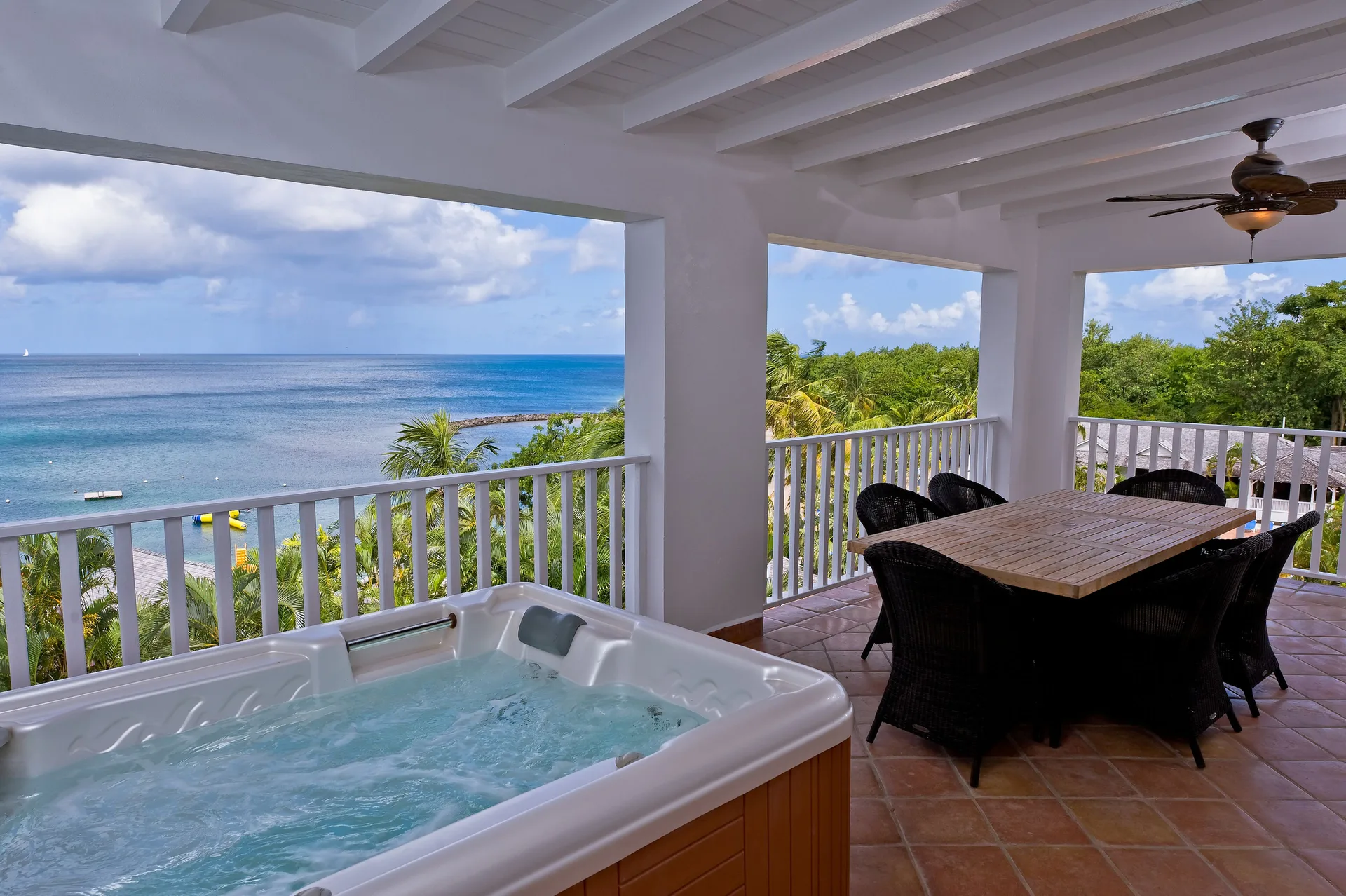 Covered terrace with hot tub and dining table at Windjammer Landing Resort and Residences.