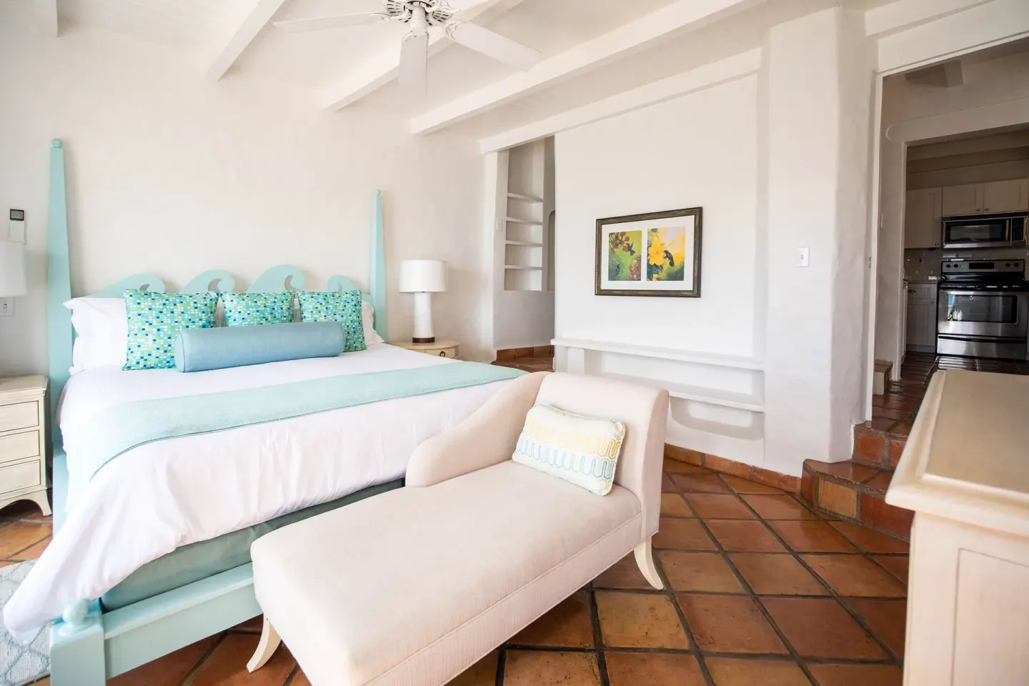Guest room at Windjammer Landing Resort and Residences with aqua king bed, chaise lounge and kitchen doorway.