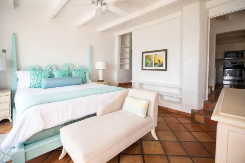 Guest room at Windjammer Landing Resort and Residences with aqua king bed, chaise lounge and kitchen doorway.
