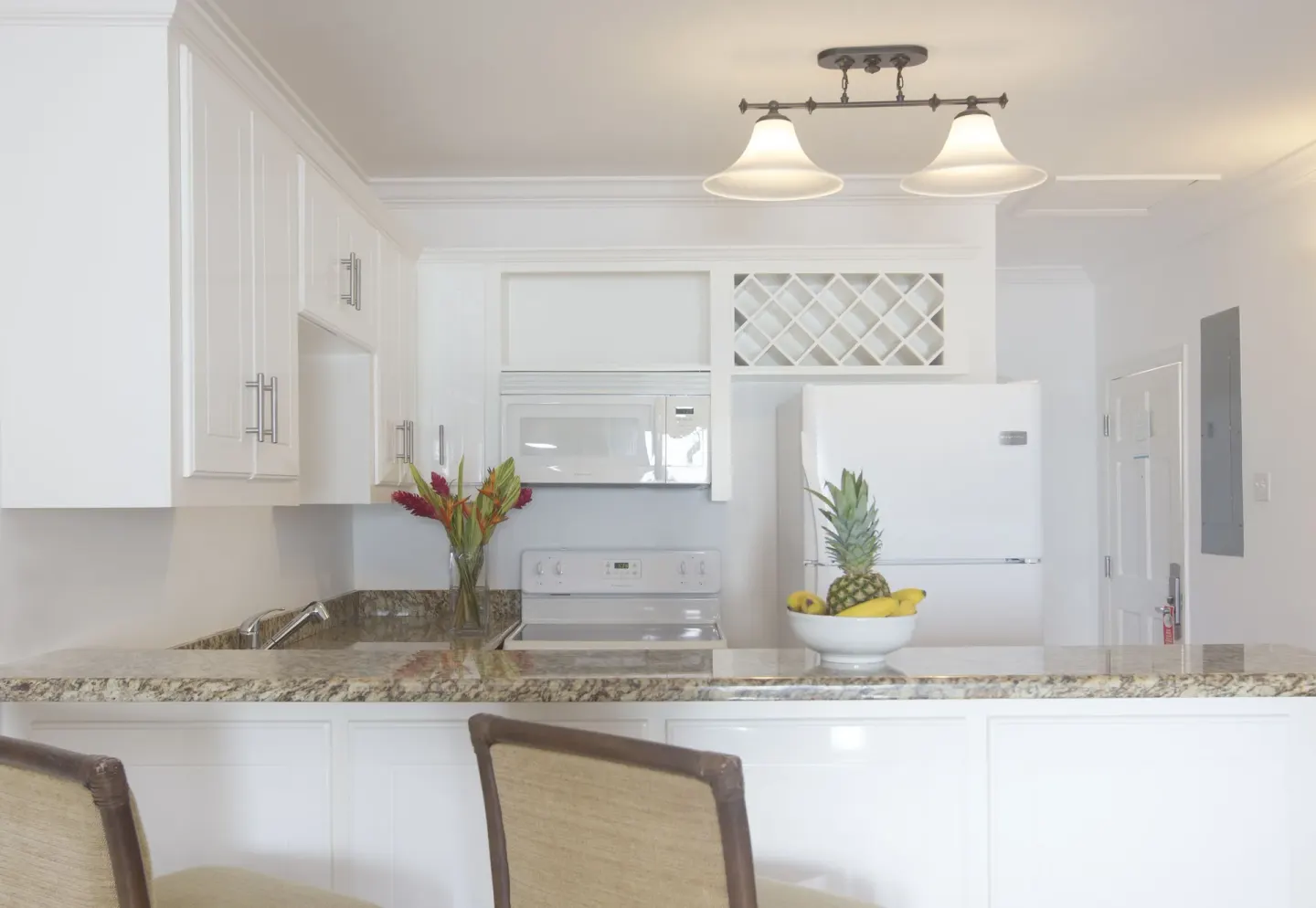 White guest room kitchen with fruit bowl at Windjammer Landing Resort and Residences.