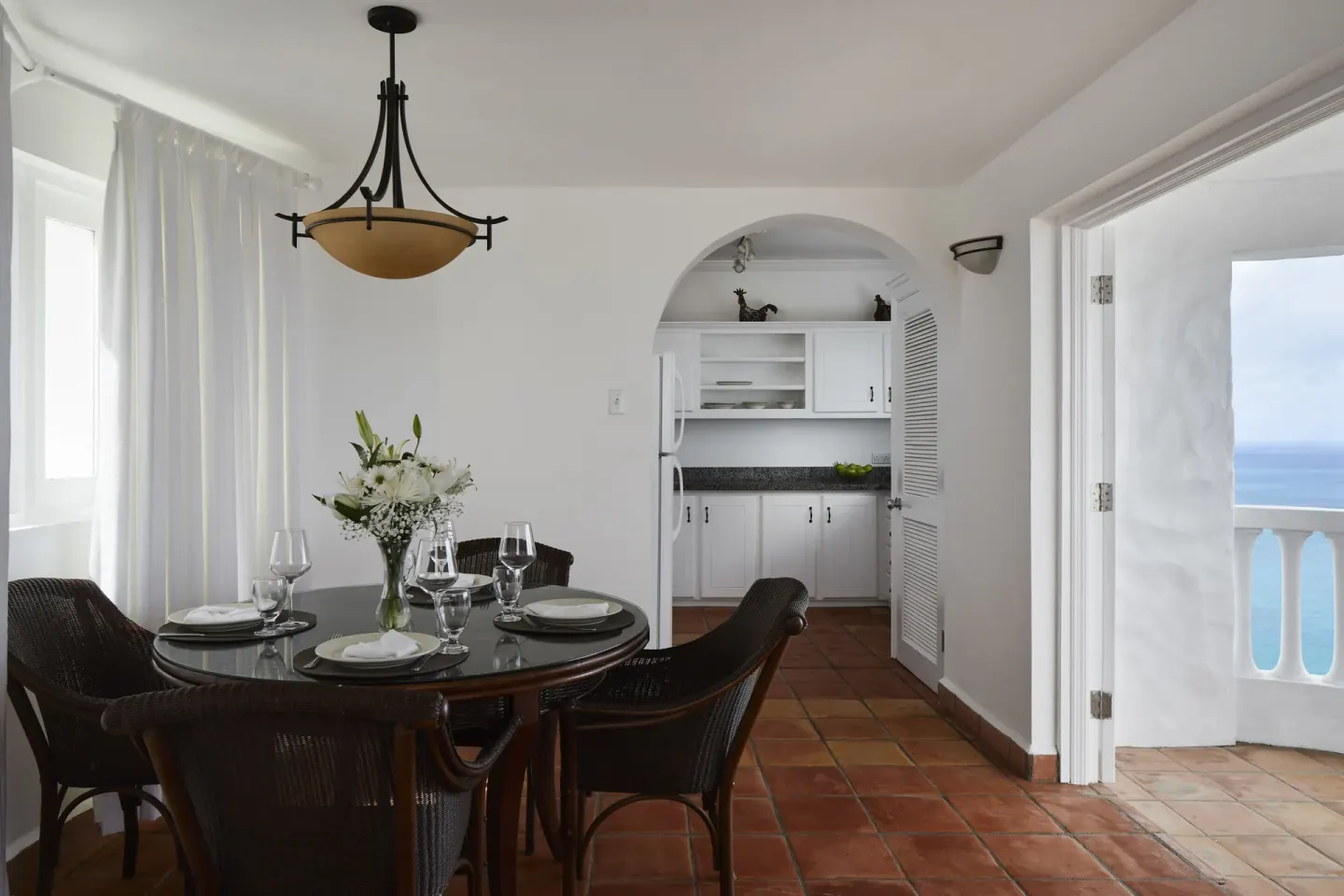 Dining area at Windjammer Landing Resort and Residences with set round table, kitchenette and ocean-view doorway.