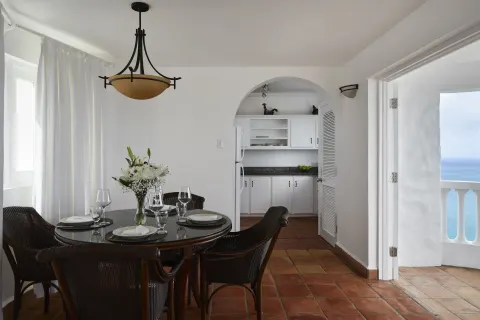 Dining area at Windjammer Landing Resort and Residences with set round table, kitchenette and ocean-view doorway.