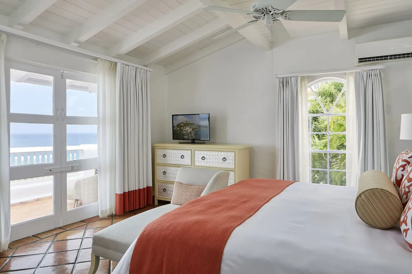 Ocean-view guest room at Windjammer Landing Resort and Residences with bed, dresser, TV and balcony doors.