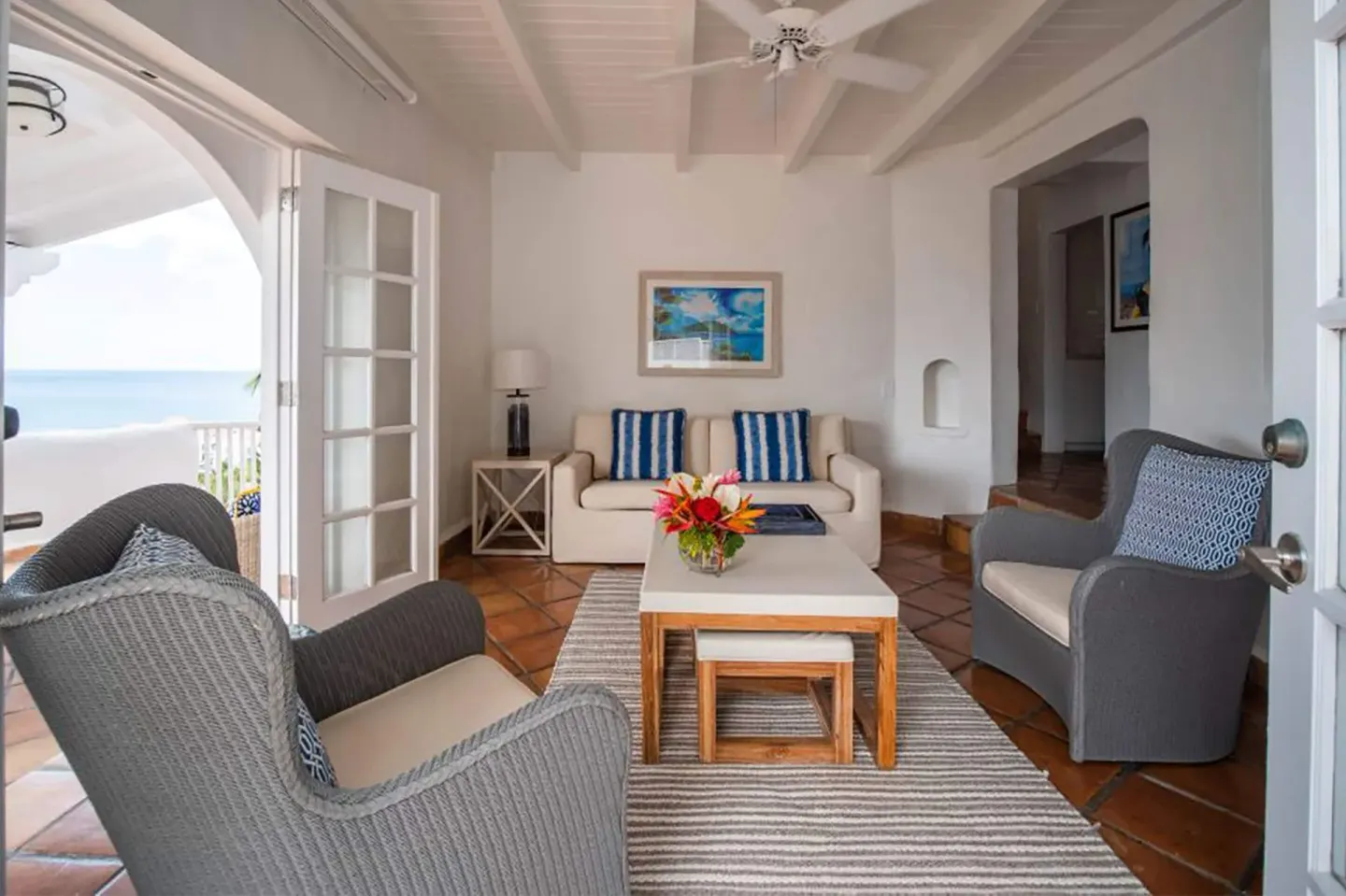 Seating area with sofa, armchairs and ocean-facing doors at Windjammer Landing Resort and Residences.