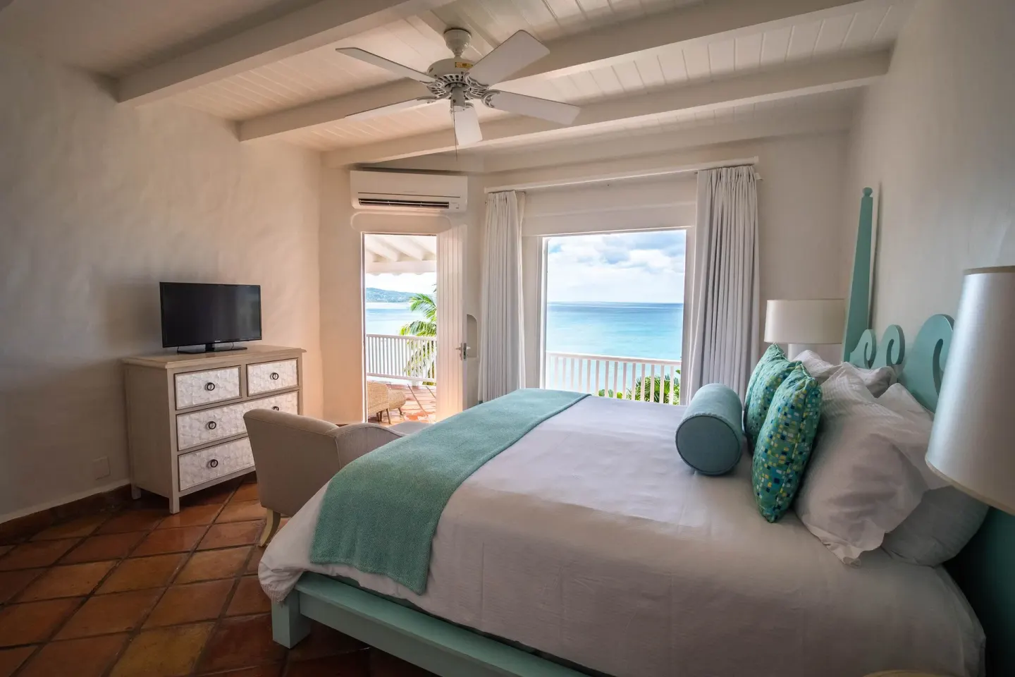 Guest room at Windjammer Landing Resort and Residences with aqua bed and direct ocean view beyond the balcony.
