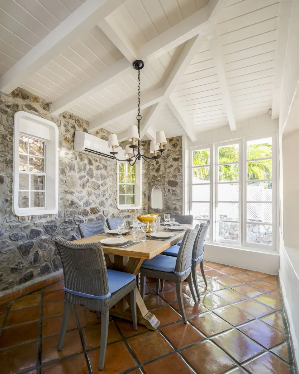 Stone-walled dining room at Windjammer Landing Resort and Residences with set table and bright windows.