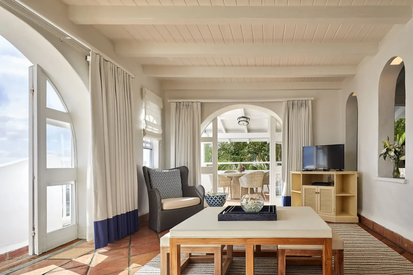 Guest living room with arched doors, terrace seating and TV at Windjammer Landing Resort and Residences.