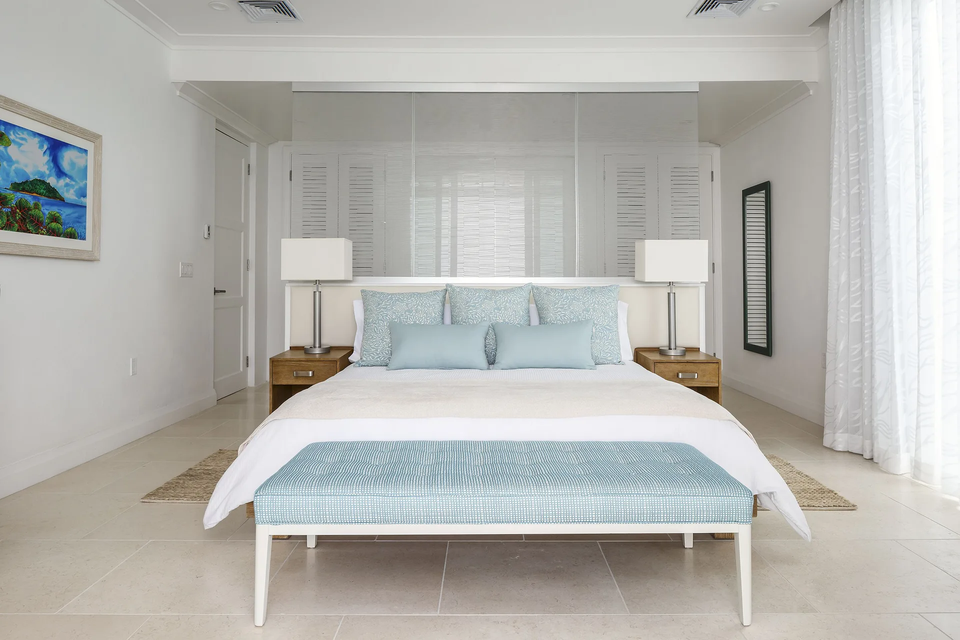 King bed with blue bench and bedside lamps at Windjammer Landing Resort and Residences.