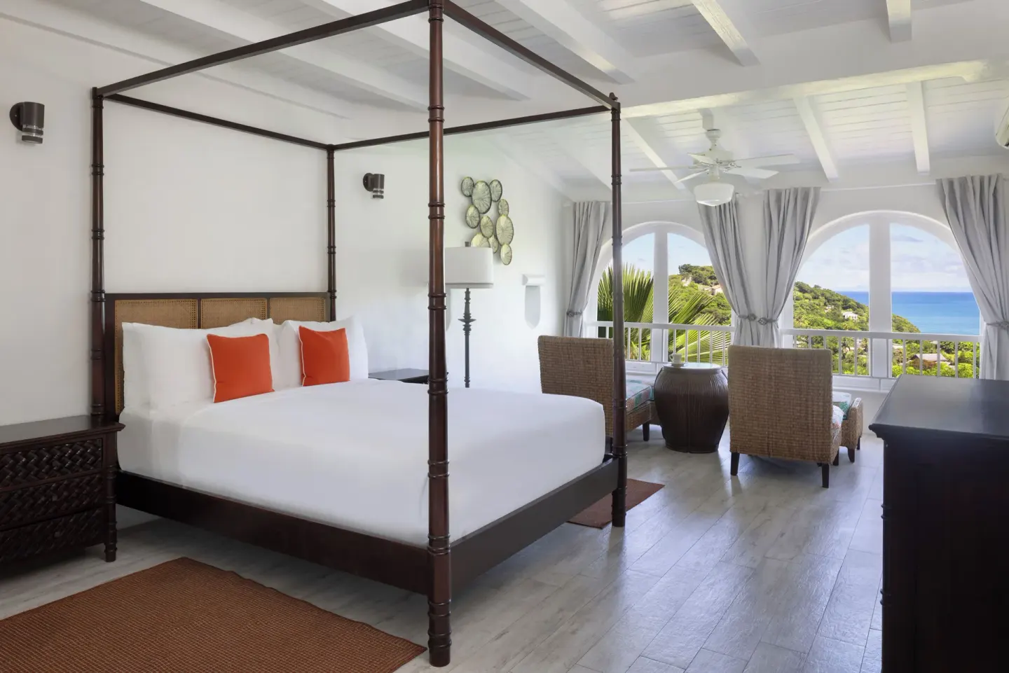 Oasis guest room with four-poster bed and sea-view sitting area at Windjammer Landing Resort and Residences.