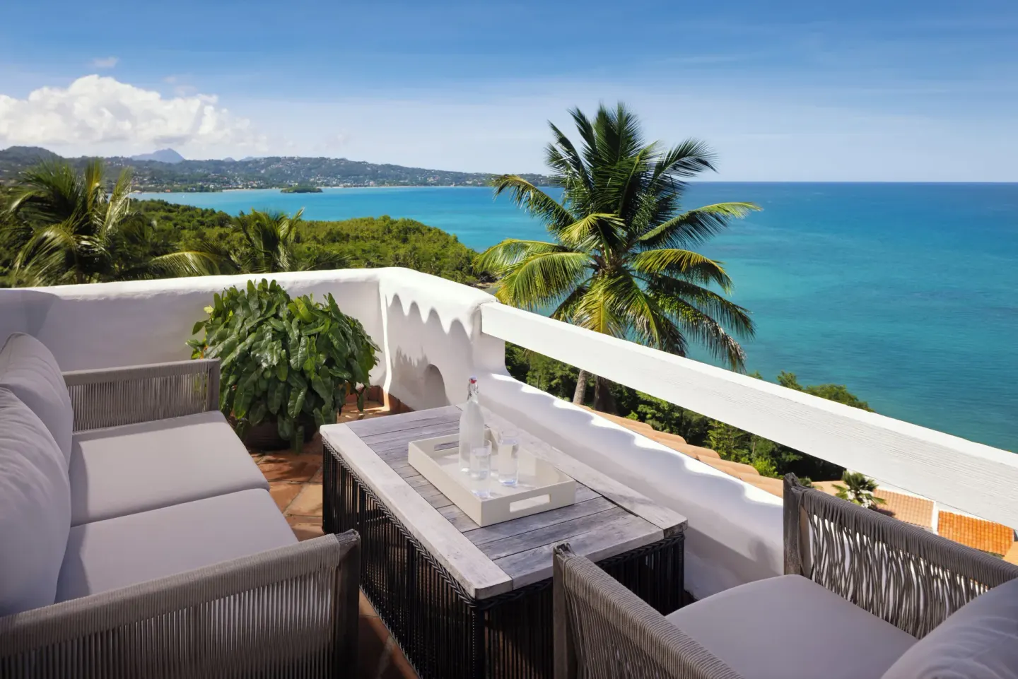 Sea-view terrace of a four-bedroom hilltop villa at Windjammer Landing Resort and Residences with outdoor seating.