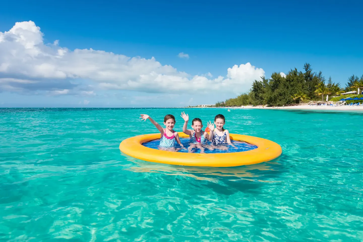 Children floating in clear turquoise sea near the beach at Windsong on the Reef.