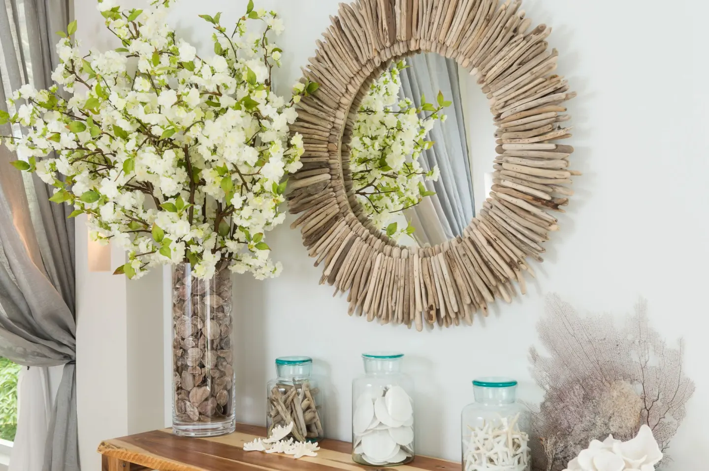 Coastal wall decor with a driftwood mirror and floral arrangement at Windsong on the Reef.